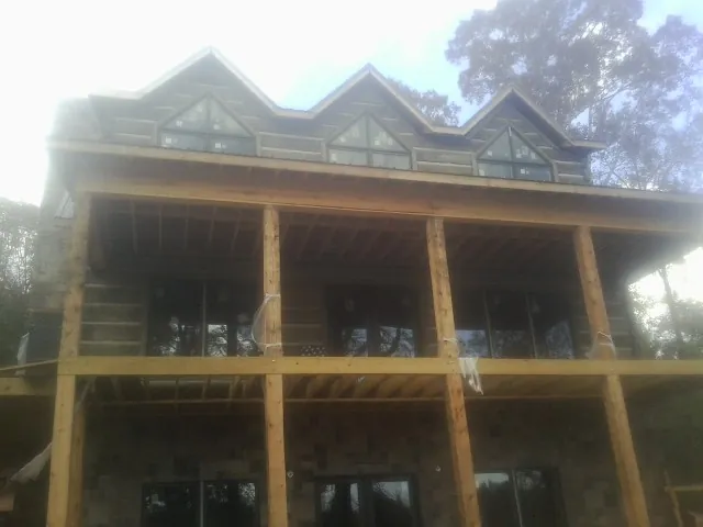 Dormers and porch framing on a large log home under construction — Roof Coating work by our crew in Ochlocknee