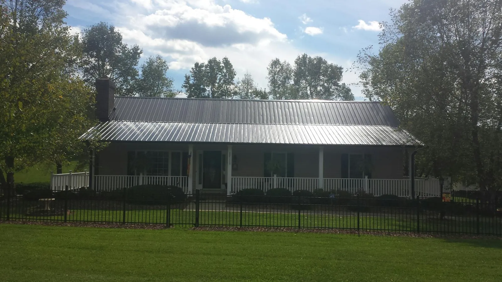 Gray metal roof on a brick ranch with a full width front porch — Gutter Guard Installation work by our crew in Ochlocknee