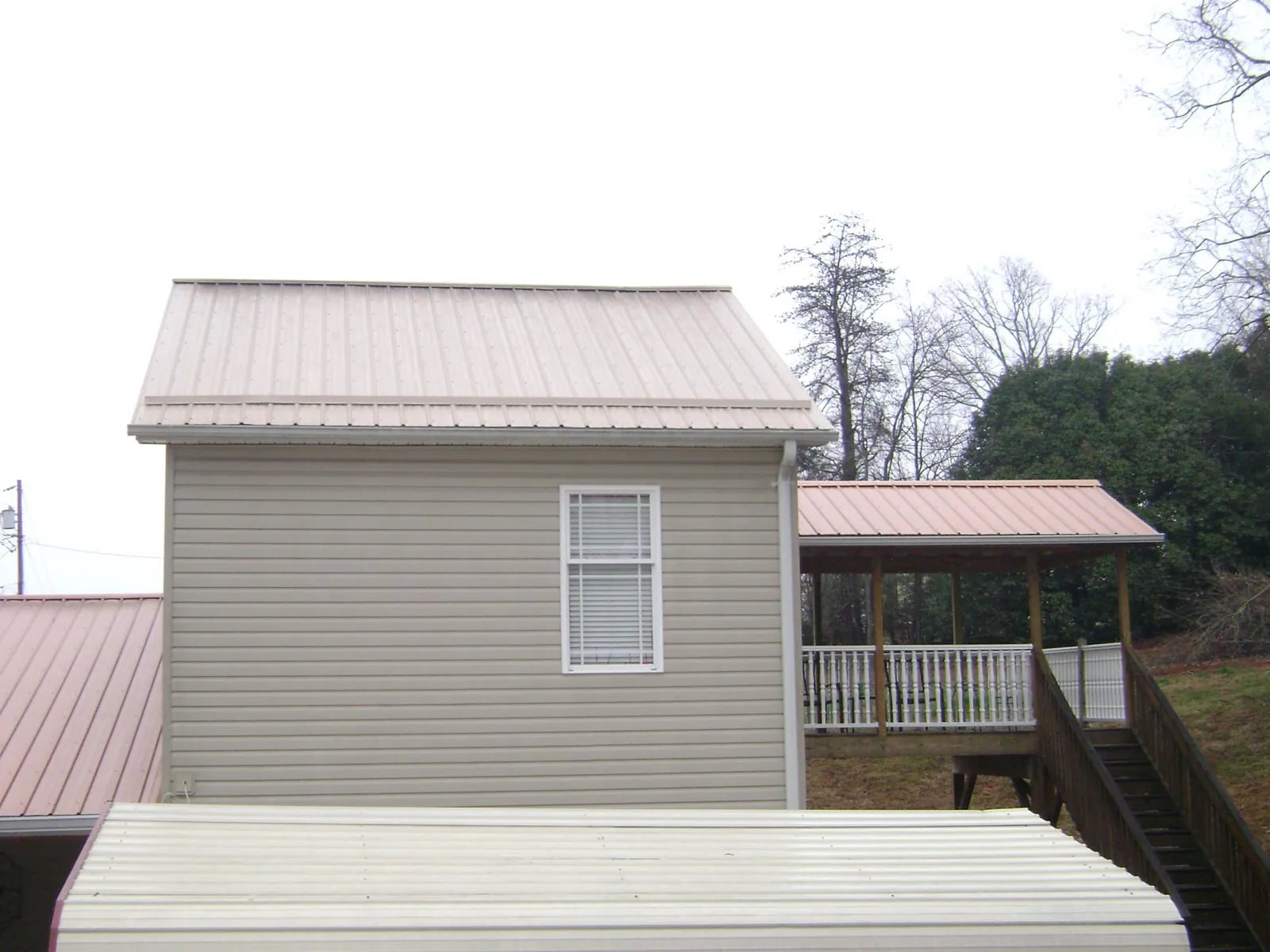 Tan metal roofs on a two story addition and attached porch, from a Roof Replacement job in Ochlocknee